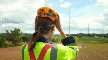 A smart engineer is putting a protective helmet on head at electrical turbines field video