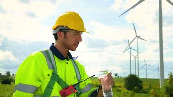 Smart engineer wearing protective helmet drinking water while  working at electrical turbines field video