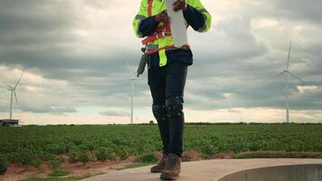 Smart engineer with protective helmet holding the blueprint working at electrical turbines field video