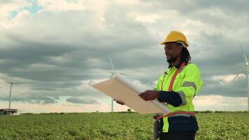 Smart engineer with protective helmet holding the blueprint working at electrical turbines field video