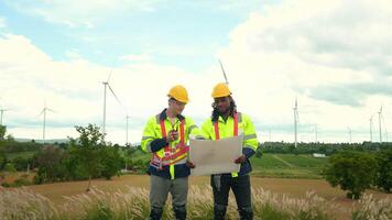 Smart engineer with protective helmet holding the blueprint working at electrical turbines field video