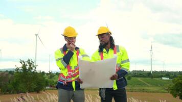 Smart engineer with protective helmet holding the blueprint working at electrical turbines field video