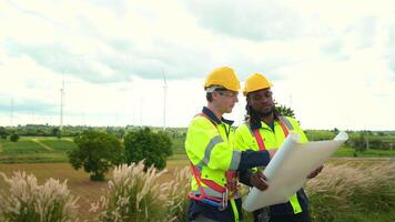 Smart engineer with protective helmet holding the blueprint working at electrical turbines field video