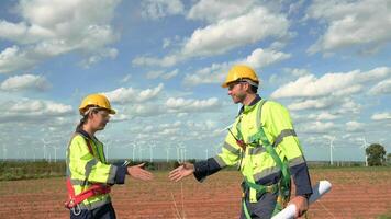 Smart engineers with protective helmet shaking hands at electrical turbines field video