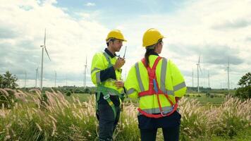 een slim ingenieur met beschermend helm Aan hoofd, gebruik makend van walkie talkie Bij elektrisch turbines veld- video