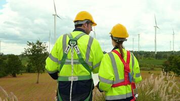 inteligente engenheiro com protetora capacete segurando a projeto trabalhando às elétrico turbinas campo video