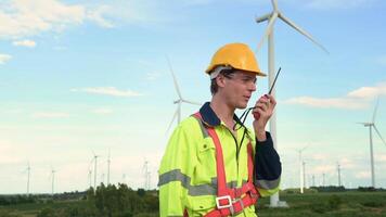 A smart engineer with protective helmet on head, using walkie talkie at electrical turbines field video
