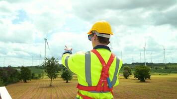 A smart engineer with protective helmet on head, using smartphone at electrical turbines field video