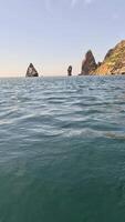 mar água superfície. Câmera moscas sobre a calma azul mar com vulcânico rochoso margens em fundo. ninguém. feriado lazer conceito. abstrato náutico verão oceano natureza. lento movimento. fechar acima. video