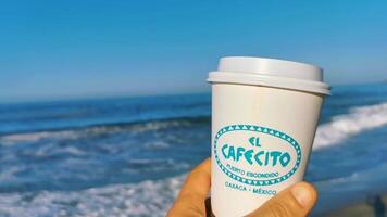 Puerto Escondido Oaxaca Mexico 2023 Coffee to go mug on the beach sand sea waves. video