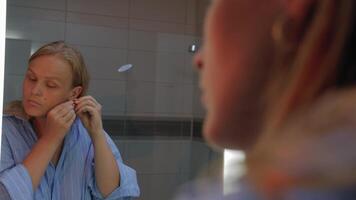 kvinna applicering örhänge i reflexion av badrum video