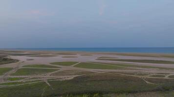 aéreo tiro do costeiro zonas úmidas às crepúsculo com padrões dentro areia e mar video