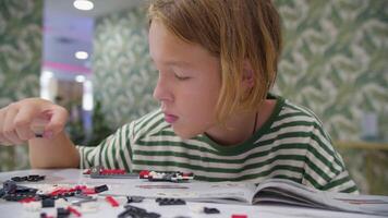 Teen assembling plastic block constructor at cafe video