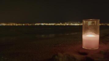 Candle aglow with blurred city lights on beach video