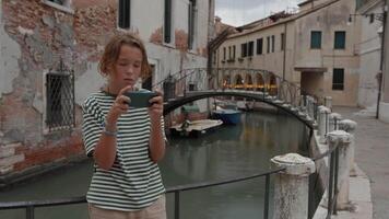 garçon avec téléphone intelligent près vénitien canal video