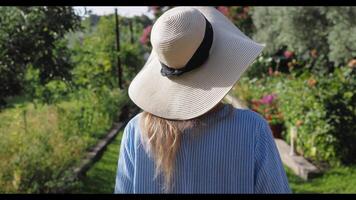 kvinna i hatt gående genom trädgård - steadicam skott video