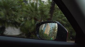 Raindrops on car window with side mirror view video