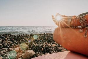 mujer mar yoga. contento mujer en blanco traje de baño y boho estilo pulseras practicando al aire libre en yoga estera por mar en puesta de sol. mujer yoga aptitud rutina. sano estilo de vida, armonía y meditación foto