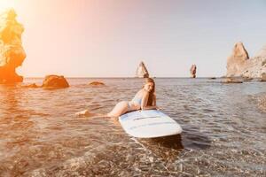 Woman sea sup. Close up portrait of happy young caucasian woman with long hair looking at camera and smiling. Cute woman portrait in a blue bikini posing on sup board in the sea photo