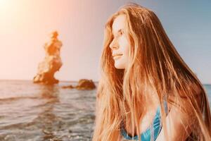 mujer mar sorber. cerca arriba retrato de contento joven caucásico mujer con largo pelo mirando a cámara y sonriente. linda mujer retrato en un azul bikini posando en cenar tablero en el mar foto