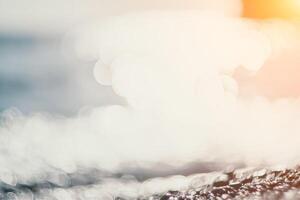 Abstract nature summer ocean sunset sea background. Small waves on water surface in motion blur with bokeh lights from sunrise. Holiday, vacation and recreational background concept. photo