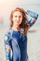 Portrait woman sea. Well looking middle aged woman with black hair, fitness instructor in blue swimwear on the rocky beach near the sea. Female fitness yoga routine concept. Healthy lifestyle. photo