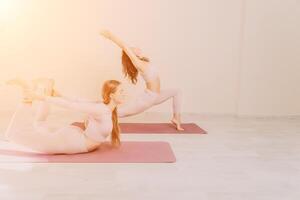 bien mirando medio Envejecido deportivo mujer, aptitud instructor en rosado ropa de deporte haciendo extensión y pilates en yoga estera en el estudio con espejo. hembra aptitud yoga. sano estilo de vida y armonía. foto