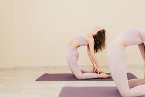 bien mirando medio Envejecido deportivo mujer, aptitud instructor en rosado ropa de deporte haciendo extensión y pilates en yoga estera en el estudio con espejo. hembra aptitud yoga. sano estilo de vida y armonía. foto