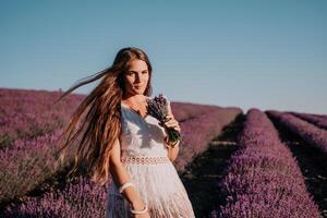 mujer lavanda campo. contento despreocupado mujer en un blanco vestir caminando en un lavanda campo y oliendo un lavanda ramo de flores en puesta de sol. ideal para calentar y inspirador conceptos en pasión de viajar y viajar. foto