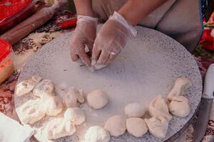 mujer manos haciendo qutab o chebureki con un laminación alfiler y picado carne cebolla en masa para culinario conceptos relacionado a azerbaiyano, tártaro y griego cocina, como bien como empanadas en latín America. foto