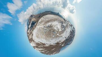 Winter snow mountain panorama. 360 little planet panorama aerial view above sea and snow covered frozen mountains with deep blue sky and a beautiful radiant sun. Cold weather and climate change photo