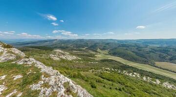 Wide panoramic view on mountain landscape with lush green hills under clear blue sky, tranquil natural beauty, perfect for outdoor enthusiasts. photo