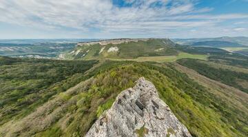 amplio panorámico ver en montaña paisaje con lozano verde colinas debajo claro azul cielo, tranquilo natural belleza, Perfecto para al aire libre entusiastas foto