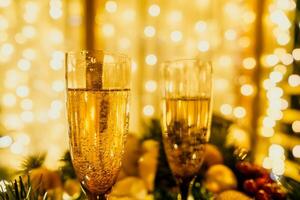 Two champagne glasses filled with champagne are placed on a table with a fruit arrangement. The glasses are surrounded by lights, creating a festive atmosphere. photo