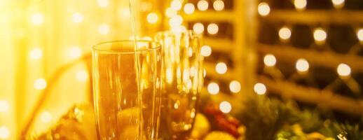 Two champagne glasses filled with champagne are placed on a table with a fruit arrangement. The glasses are surrounded by lights, creating a festive atmosphere. photo