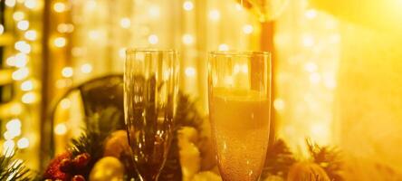 Two champagne glasses filled with champagne are placed on a table with a fruit arrangement. The glasses are surrounded by lights, creating a festive atmosphere. photo