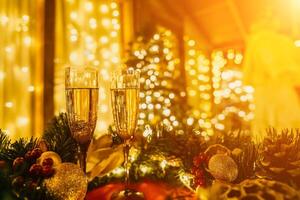 Two champagne glasses filled with champagne are placed on a table near to Christmas tree. The glasses are surrounded by lights, creating a festive atmosphere. photo