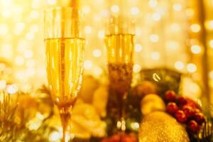 Two champagne glasses filled with champagne are placed on a table with a fruit arrangement. The glasses are surrounded by lights, creating a festive atmosphere. photo