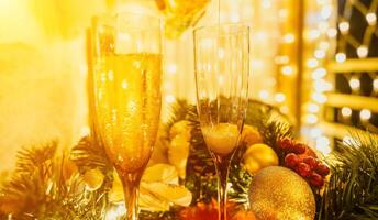 Two champagne glasses filled with champagne are placed on a table with a fruit arrangement. The glasses are surrounded by lights, creating a festive atmosphere. photo