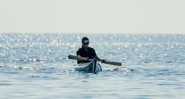 mujer mar kayac. contento sonriente mujer en kayac en océano, remar con de madera remo. calma mar agua y horizonte en antecedentes. activo estilo de vida a mar. verano vacaciones. foto