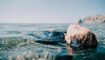 Woman swimming in sea at sunset, float on calm water back view. Concept of body image and fitness, enjoying a serene beach. Happy woman with perfect fit body enjoys sea beach photo