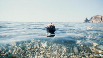 Woman swimming in sea at sunset, float on calm water back view. Concept of body image and fitness, enjoying a serene beach. Happy woman with perfect fit body enjoys sea beach photo