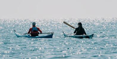 Man woman sea kayak. Happy free man and woman in kayak on ocean, paddling with wooden oar. Calm sea water and horizon in background. Active lifestyle at sea. Summer vacation. photo