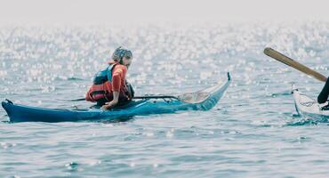 Man woman sea kayak. Happy free man and woman in kayak on ocean, paddling with wooden oar. Calm sea water and horizon in background. Active lifestyle at sea. Summer vacation. photo