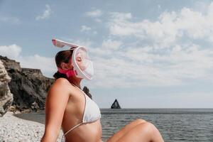 joven contento mujer en blanco bikini y vistiendo rosado máscara obtiene Listo para mar bucear. positivo sonriente mujer relajante y disfrutando agua ocupaciones con familia verano viaje Días festivos vacaciones en mar. foto