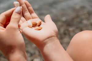 Woman eating milky almond nuts. A young caucasian woman chopping fresh green almond after morning fitness yoga near sea. Only hands are visibly. Healthy vegan food. Slow motion. Close up photo