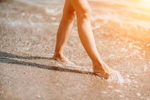 un mujer camina a lo largo el playa, piernas de cerca. descalzo mujer sta foto