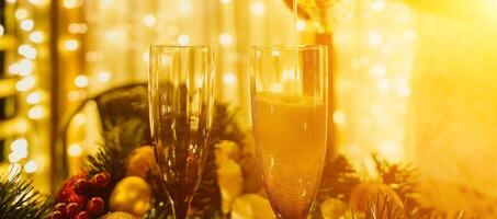 Two champagne glasses filled with champagne are placed on a table with a fruit arrangement. The glasses are surrounded by lights, creating a festive atmosphere. photo