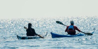 Man woman sea kayak. Happy free man and woman in kayak on ocean, paddling with wooden oar. Calm sea water and horizon in background. Active lifestyle at sea. Summer vacation. photo