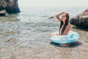 Woman summer sea. Happy woman swimming with inflatable donut on the beach in summer sunny day, surrounded by volcanic mountains. Summer vacation concept. photo